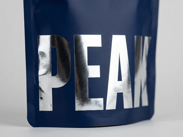 Chrome-silver lettering catching the light against a matte navy pouch